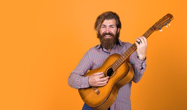 uomo bello e brutale con i baffi suona la chitarra musicista e cantante maturo chitarrista casuale di stile moderno hipster barbuto con chitarra acustica maggiore musica maggiore