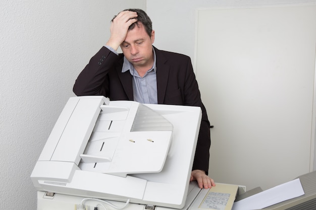 Uomo bello e sollecitato che per mezzo di una macchina della copia