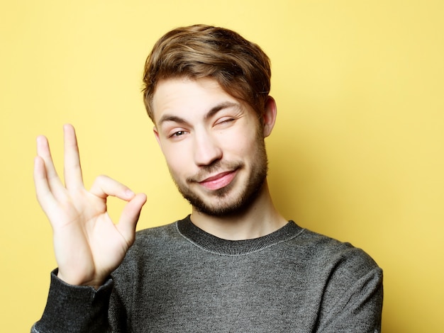 Uomo bello felice che mostra i pollici in su sopra lo spazio giallo