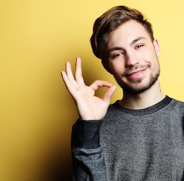 Uomo bello felice che mostra i pollici in su