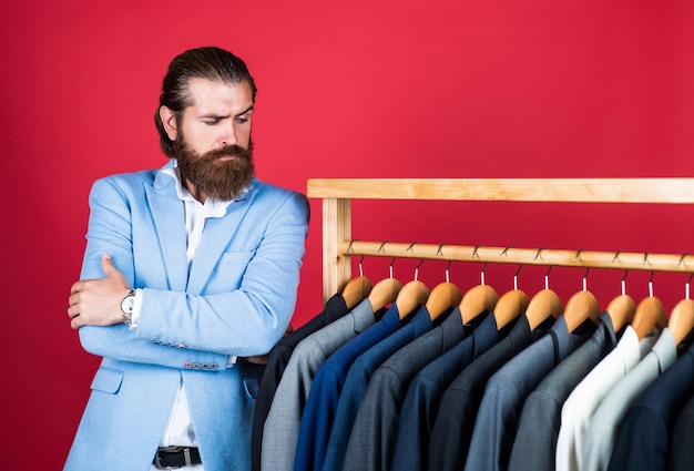 Uomo bello in abbigliamento casual elegante guardando abiti e scegliendo abiti da uomo alla moda su appendiabiti in camera stile moda business stile servizio di lavaggio a secco stile e concetto di persone