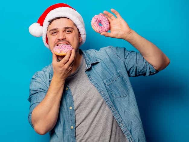 Uomo bello in cappello di natale con le ciambelle