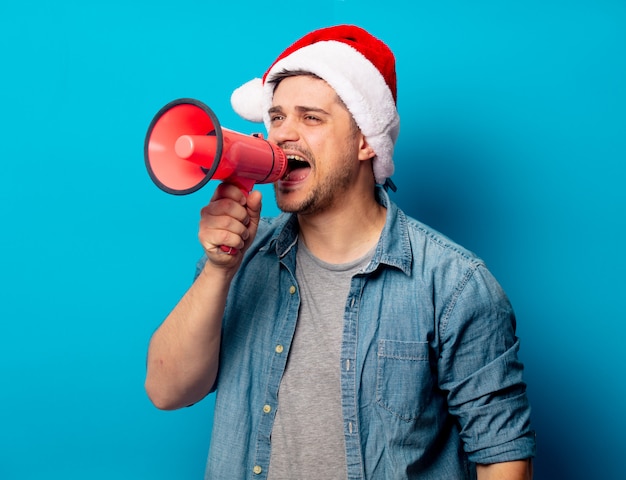 Uomo bello in cappello di natale con megafono