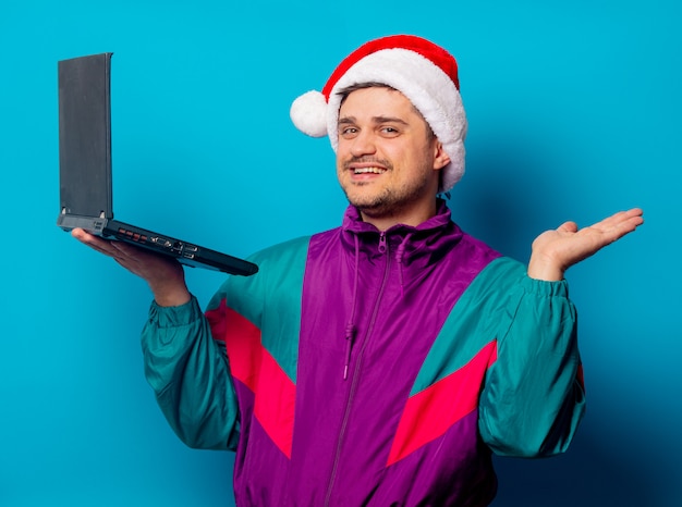 Uomo bello in cappello di Natale e giacca anni '90 con il portatile