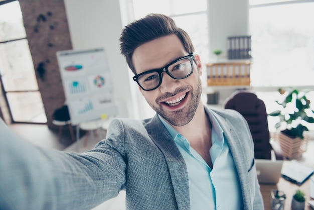 Uomo bello in vestito che prende selfie alla scrivania