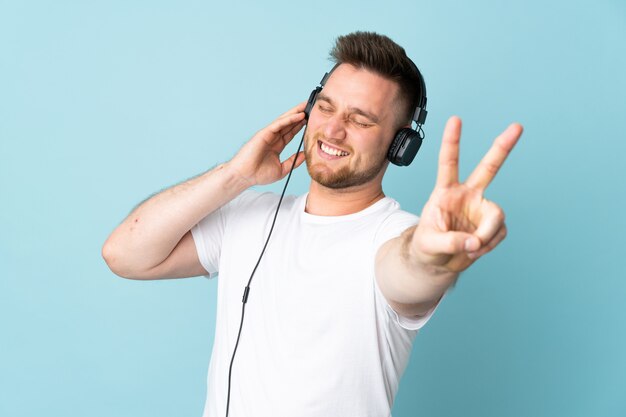 Uomo bello isolato su musica d'ascolto e sul canto della parete blu