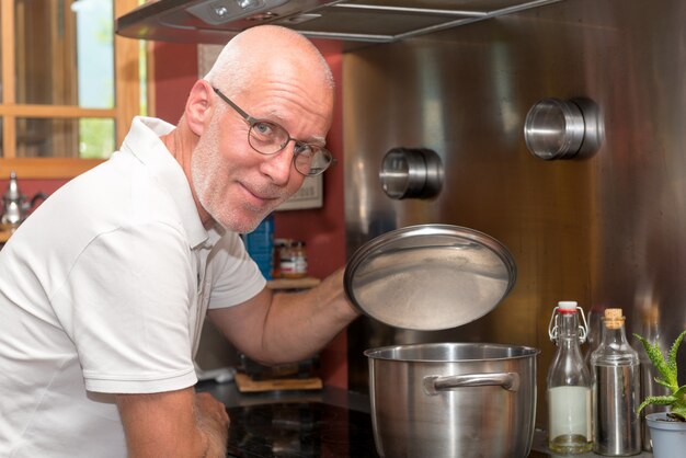 Uomo bello maturo che cucina nella cucina domestica