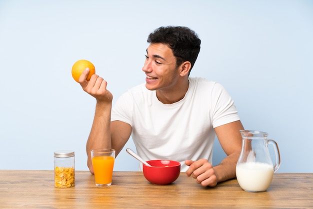 Uomo bello nel fare colazione e tenere un'arancia