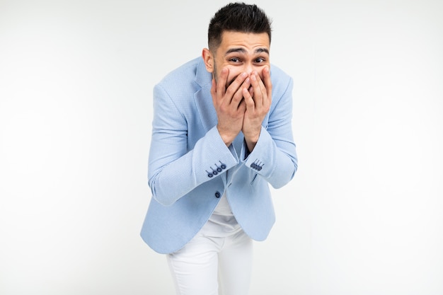 Uomo bello nelle risate di stile classico che copre la bocca con la mano su uno sfondo bianco isolato