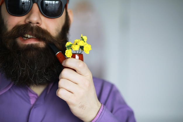 Uomo bello o hipster barbuto boscaiolo con barba e baffi in camicia con pipa