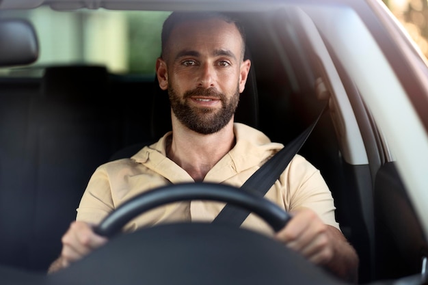 Uomo bello sorridente alla guida di un'auto, viaggio su strada. Cintura di sicurezza, concetto di guida sicura