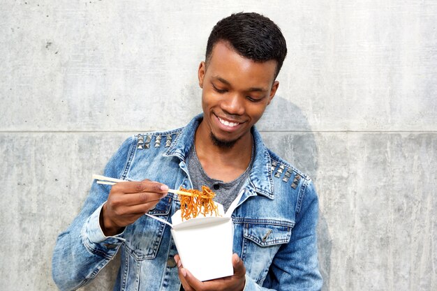 Uomo bello sorridente che gode delle tagliatelle da portar via