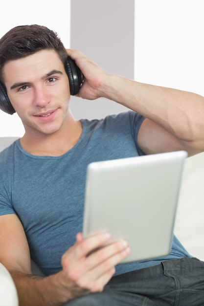 Uomo bello sorridente che per mezzo della compressa che ascolta la musica