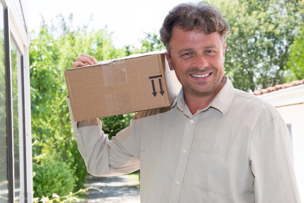 Uomo bello sorridente con il pacco per la consegna