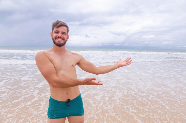 Uomo bello sulla spiaggia che indica