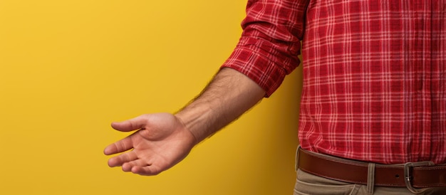 Uomo bianco in camicia a quadri rossa sfondo giallo con spazio vuoto a portata di mano e mano sul fianco