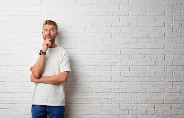 Uomo biondo bello che pensa contro una parete del grunge