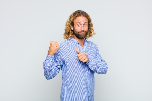 Uomo biondo che sorride allegramente e con indifferenza indicando lo spazio di copia sul lato, sentendosi felice e soddisfatto