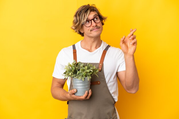 Uomo biondo del giardiniere che tiene una pianta isolata