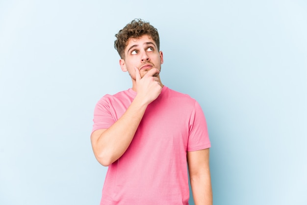 Uomo biondo giovane dei capelli ricci che pensa e che guarda su, essendo riflettente, contemplando, avendo una fantasia