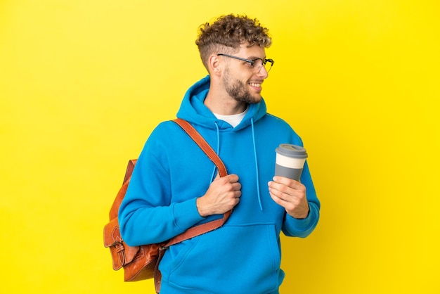 Uomo biondo giovane studente isolato su sfondo giallo guardando lato