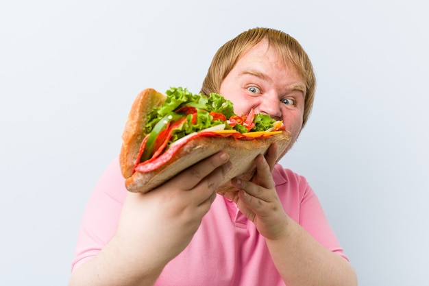 Uomo biondo pazzo caucasico che tiene un panino gigante