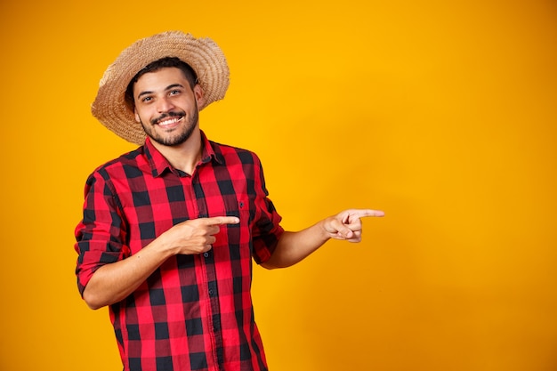 Uomo brasiliano che indossa abiti tipici per la Festa Junina che punta di lato