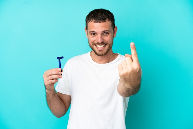 Uomo brasiliano che si rade la barba isolato su sfondo blu facendo un gesto imminente