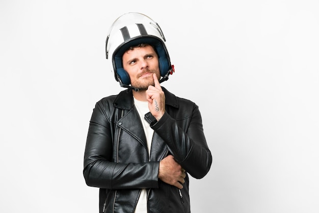 Uomo brasiliano con un casco da motociclista su sfondo bianco isolato che ha dubbi mentre guarda in alto
