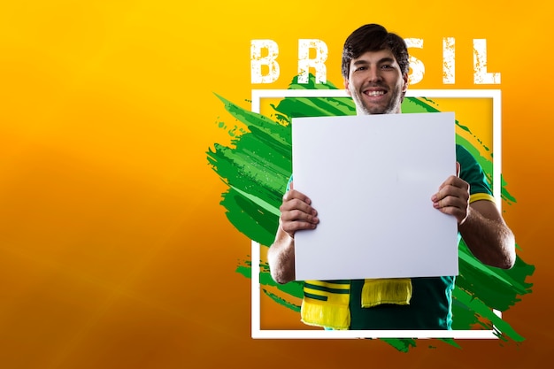 Uomo brasiliano felice, tifoso che tiene manifesto in bianco