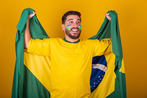 Uomo brasiliano latinoamericano tifo per il brasile nella coppa del mondo 2022 nazionalista patriota Bandiera brasiliana vibrante tifo e salto simbolo di felicità, gioia e celebrazione con bandiera brasiliana