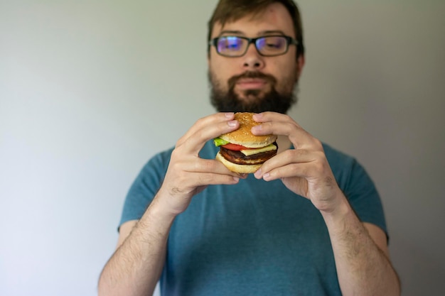 Uomo bruna con gli occhiali guardando hamburger prima di mangiare hamburger fatti in casa