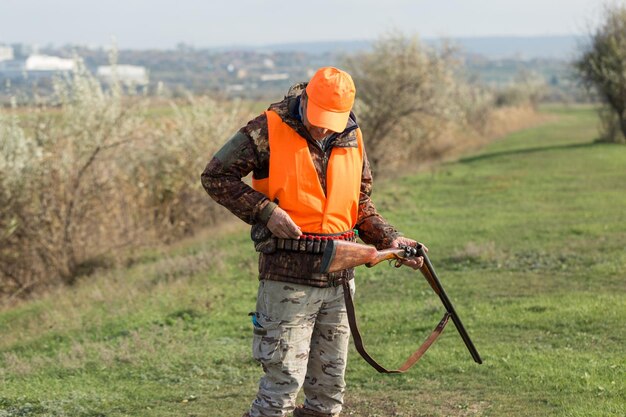 Uomo cacciatore in mimetica con una pistola durante la caccia alla ricerca di uccelli selvatici o selvaggina Stagione di caccia autunnale