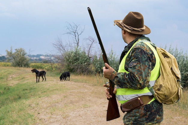 Uomo cacciatore in mimetica con una pistola durante la caccia alla ricerca di uccelli selvatici o selvaggina Stagione di caccia autunnale