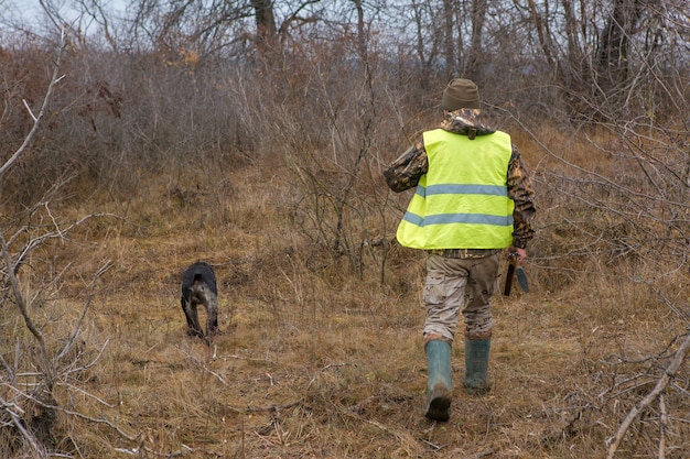 Uomo cacciatore in mimetica con una pistola durante la caccia alla ricerca di uccelli selvatici o selvaggina. Stagione di caccia autunnale.