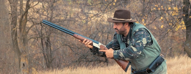 Uomo cacciatore in mimetica con una pistola durante la caccia alla ricerca di uccelli selvatici o selvaggina