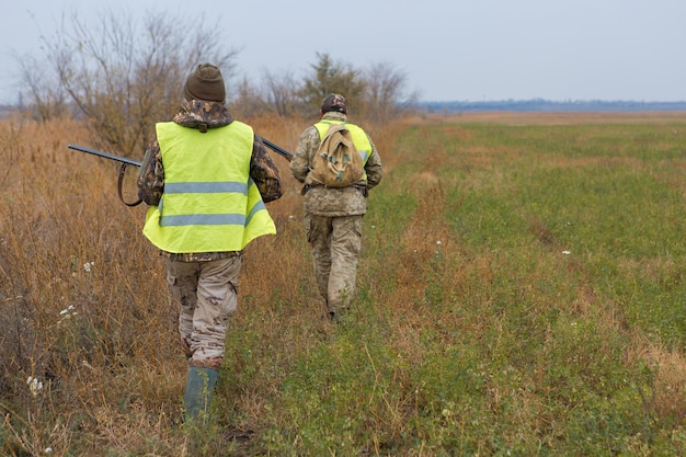 Uomo cacciatore in mimetica con una pistola durante la caccia alla ricerca di uccelli selvatici o selvaggina