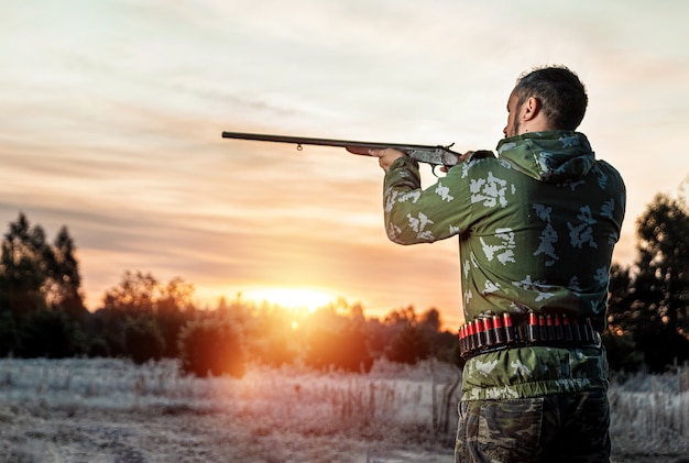 Uomo cacciatore in mimetica con una pistola durante la caccia