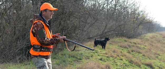 Uomo cacciatore mimetico con pistola durante la caccia alla ricerca di uccelli selvatici o selvaggina