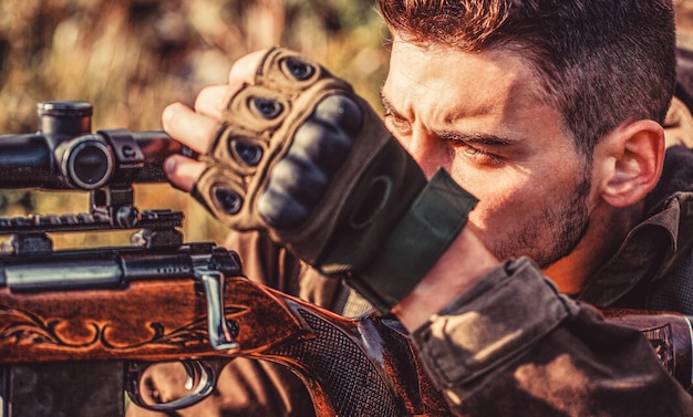 Uomo cacciatore. Periodo di caccia. Maschio con una pistola. Avvicinamento. Cacciatore con fucile da caccia e forma da caccia per cacciare. Il cacciatore sta mirando