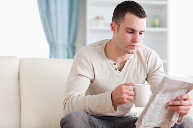 Uomo calmo che mangia un tè mentre leggendo le notizie