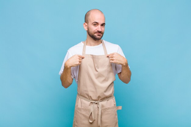 Uomo calvo che guarda orgoglioso, positivo e casual che punta al petto con entrambe le mani