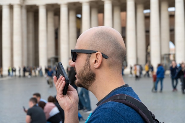 Uomo calvo che invia un messaggio vocale dal suo telefono cellulare