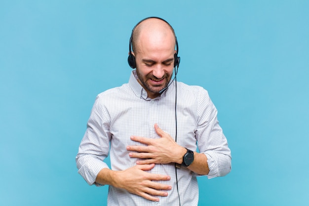 Uomo calvo che ride ad alta voce a uno scherzo esilarante, si sente felice e allegro, si diverte