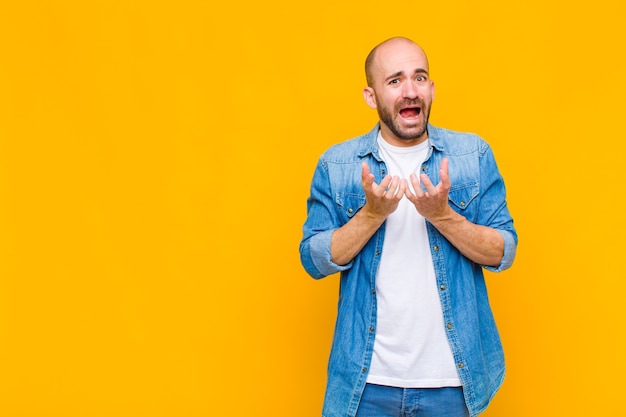 Uomo calvo che sembra disperato e frustrato, stressato, infelice e infastidito, gridando e urlando