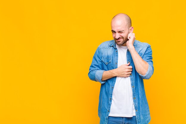 Uomo calvo che si sente stressato, frustrato e stanco, strofinando il collo doloroso, con uno sguardo preoccupato e turbato