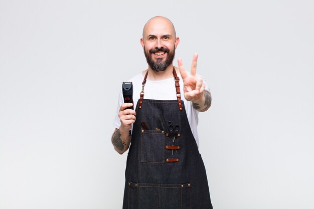 Uomo calvo che sorride e che sembra felice, spensierato e positivo, gesticolando vittoria o pace con una mano