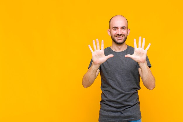 Uomo calvo sorridente e dall'aspetto amichevole, mostrando il numero dieci o decimo con la mano in avanti, conto alla rovescia