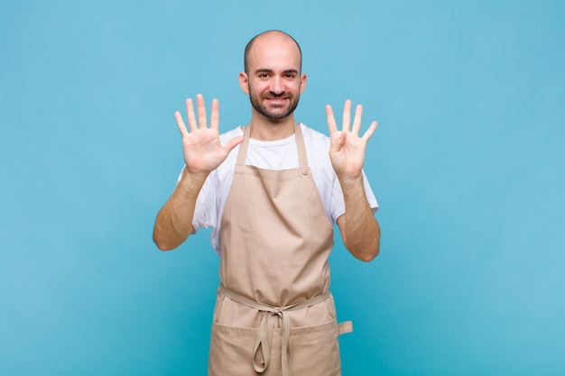 Uomo calvo sorridente e dall'aspetto amichevole, mostrando il numero nove o nono con la mano in avanti, il conto alla rovescia