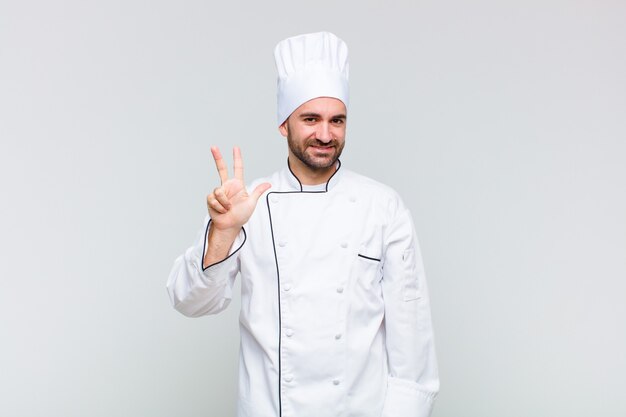 Uomo calvo sorridente e dall'aspetto amichevole, mostrando il numero tre o terzo con la mano in avanti, conto alla rovescia